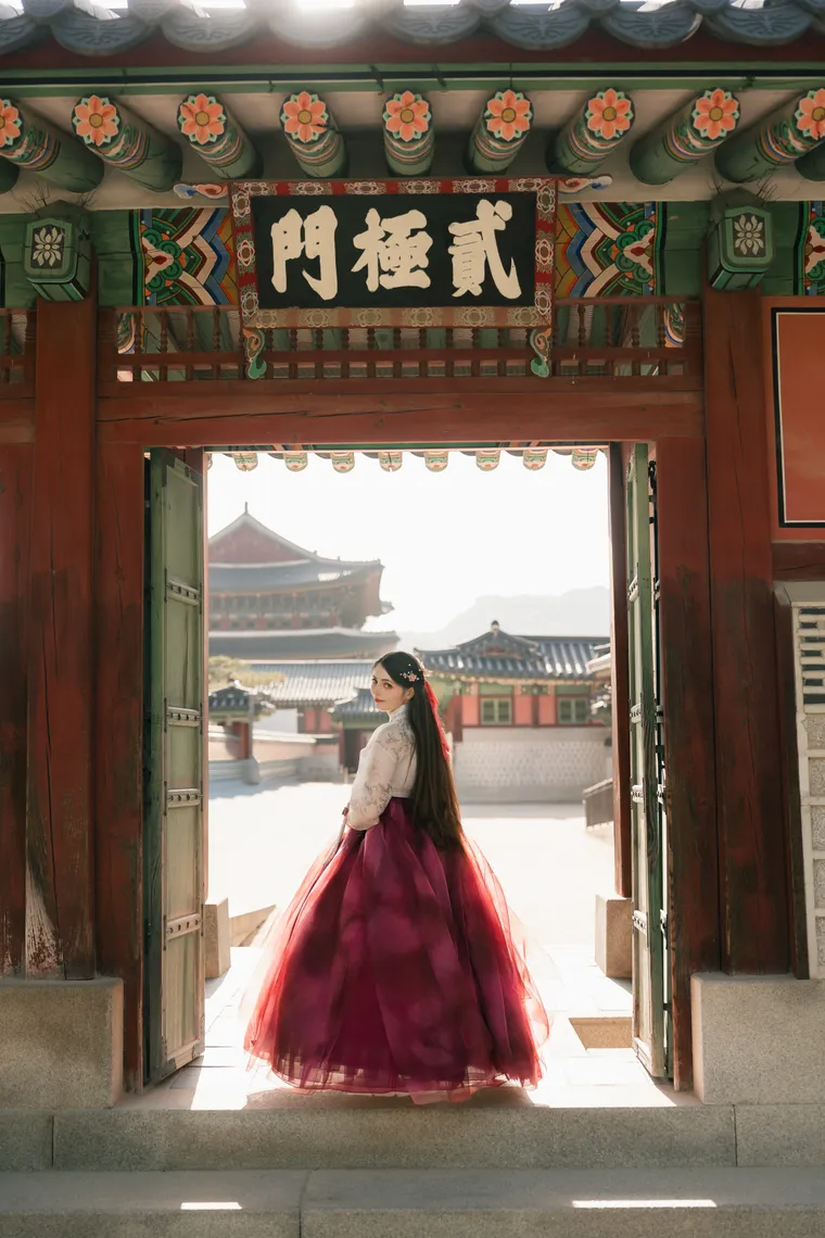 Woman in hanbok standing in a palace gate at Gyeongbokgung, palace roofs beyond